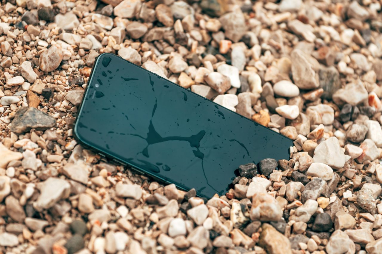 Wet smartphone lying on beach pebbles after water exposure
